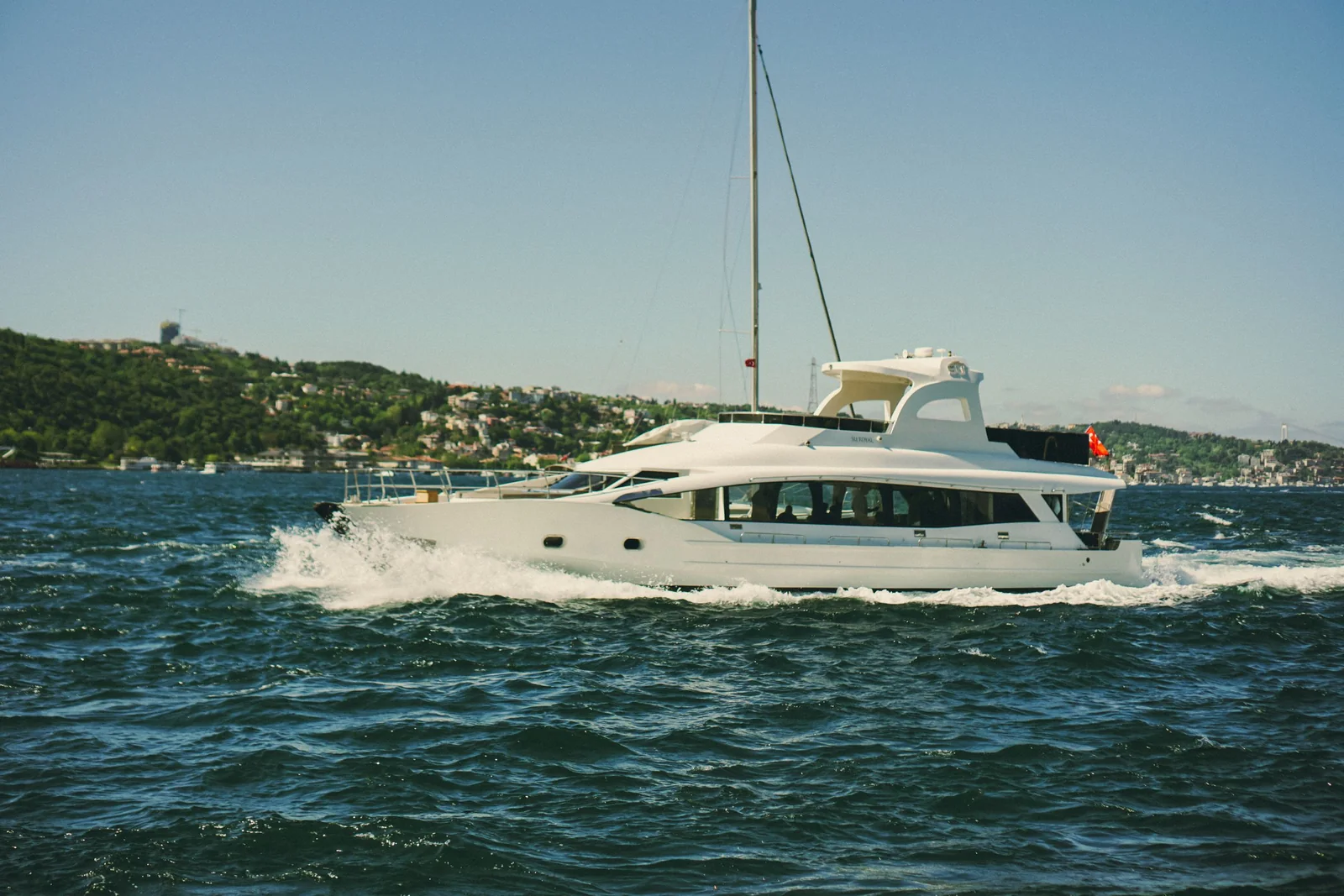A white motor yacht with dark windows cruising on the water