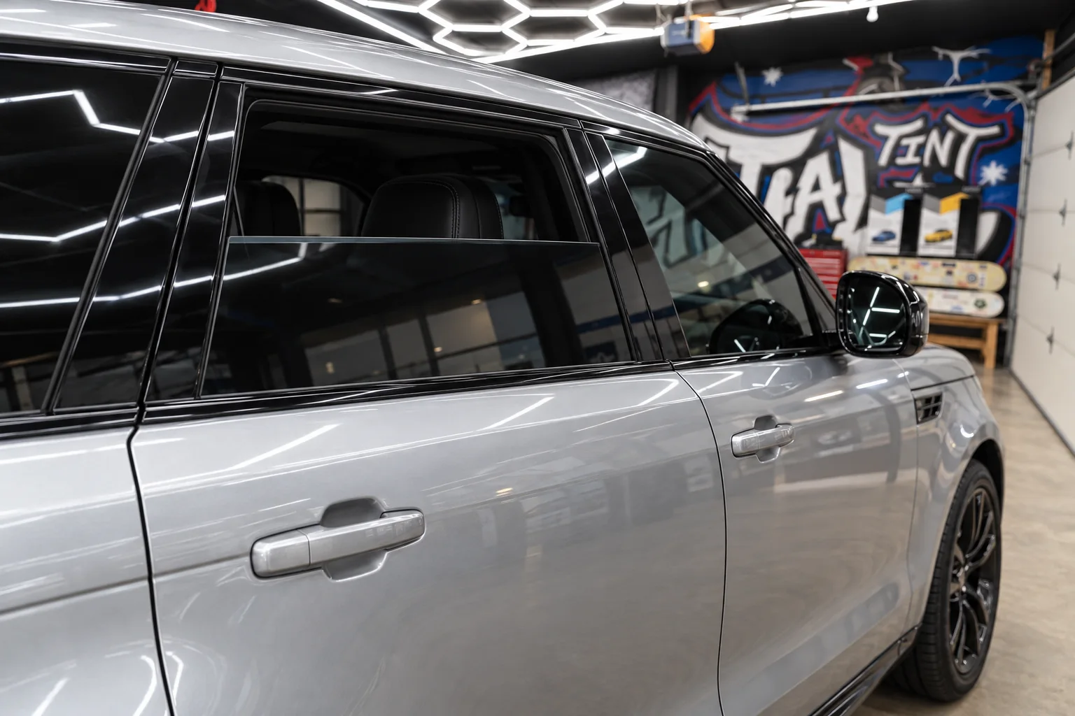 The side of a silver Range Rover Sport with tinted windows in the Presidential Tint MN shop bay